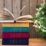Old books and Christmas tree on the wooden background