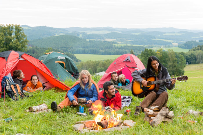 Camping students listening girl with guitar tents