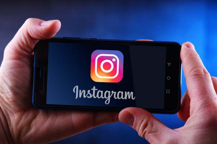 Hands holding smartphone displaying logo of Instagram